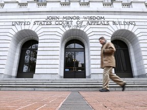 FILE - A man walks in front of the 5th U.S. Circuit Court of Appeals on Jan. 7, 2015, in New Orleans. A federal appeals court cleared the way Friday, Aug. 19, 2022, for a lawsuit to proceed against guards and officials at a privately run north Louisiana jail where an inmate died with a fractured skull in 2015. The lawsuit includes allegations that guards at Monroe's Richwood Correctional Center sometimes beat and pepper-sprayed handcuffed prisoners in an area where there were no security cameras.
