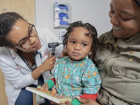In this 2019 photo provided by Zero to Three, a pediatrician checks on a child as their mother looks on at Children's National Hospital in Washington. Zero to Three's HealthySteps program aims to help children meet important milestones by placing early-childhood-development specialists in pediatric primary-care practices. (Courtesy of Zero to Three via AP)