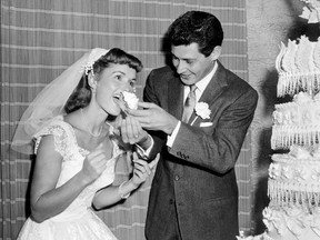 FILE - Singer Eddie Fisher feeds a piece of wedding cake to his bride, actress Debbie Reynolds following their marriage at Grossinger's in Liberty, N.Y., on Sept. 26, 1955. A raging fire broke out in a vacant building at the site of the storied Grossinger's hotel in the Catskills, Tuesday, Aug. 16, 2022, requiring the vacant structure to be demolished.