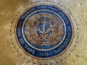 FILE - The state seal with Rhode Island's full former name appears on a rug in the state room on Nov. 4, 2021, at the Rhode Island State House, in Providence, R.I. A new report issued Monday, Aug. 22, 2022, suggests ways Providence can atone for its extensive ties to the transatlantic slave trade and centuries of racism and discrimination by, among other things, establishing home repair funds, launching financial literacy programs and boosting aid to Black and Indigenous organizations.