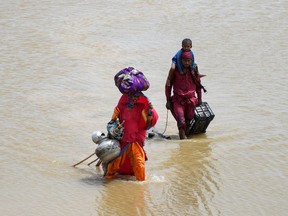 A family with their belongings wade through rain waters following rains and floods during the monsoon season in Jamshoro, Pakistan Aug. 26, 2022.