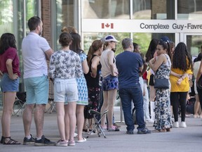 Die Bundesregierung fügt neue Passdienststellen in ganz Kanada hinzu, da die lauten Gegenreaktionen über lange Wartezeiten anhalten.  Menschen stehen vor dem Bundesgebäude von Guy Favreau Schlange, während sie darauf warten, am Sonntag, den 26. Juni 2022, in Montreal einen Pass zu beantragen.