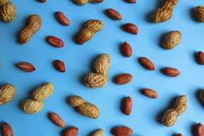 Texture of peanuts in shell and without lie on a blue background.