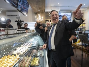 Der Premier von Quebec, Francois Legault, lächelt, als er am Dienstag, den 17. Mai 2022 in Laval, Que, einen Käsekuchenladen besucht.