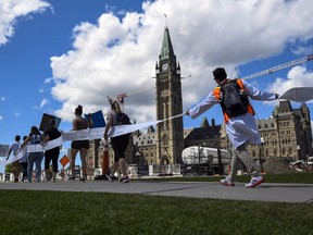 Scientists and researchers hold a 60-metre-long petition with over 7,100 signatures calling on the federal government to increase funding for graduate and post-doctoral scholars, during the “Support Our Science” rally on Parliament Hill in Ottawa, on Aug. 11, 2022.