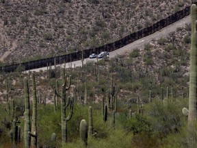 FILE - U.S. Customs and Patrol Patrol agents sit along a section of the international border wall that runs through Organ Pipe Cactus National Monument, Thursday, Aug. 22, 2019 in Lukeville, Ariz. The Border Patrol says one of its agents rescued an infant and a toddler Thursday, Aug. 25, 2022, who were left alone by migrant smugglers in the park.
