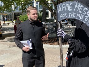 Tobias Tissen, left, speaks with a man dressed up as the grim reaper who was celebrating the group's convictions and fines as he leaves court in Winnipeg on Thursday, Aug. 25, 2022. Tissen was one of five Manitobans fined Thursday for repeated violations of the province's COVID-19 public health orders.