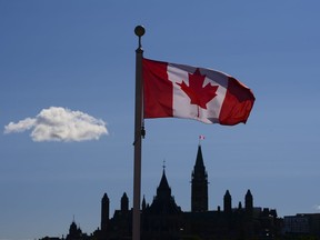 Parliament Hill is viewed below a Canada flag in Gatineau, Quebec, Friday, Sept. 18, 2020. A new survey finds more Canadians report a strong attachment to their primary language than to other markers of identity, including the country they call home.