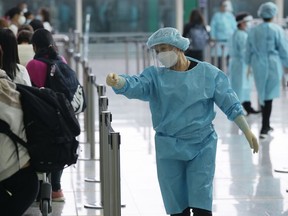 FILE - Workers wearing protective gear direct arriving passengers to quarantine hotels in the Hong Kong International Airport, Friday, April 1, 2022. Hong Kong's government says its population has shrunk for a second year as anti-virus controls hampered the inflow of new workers and births declined, but it made no mention of an exodus of residents following a crackdown on a pro-democracy movement.