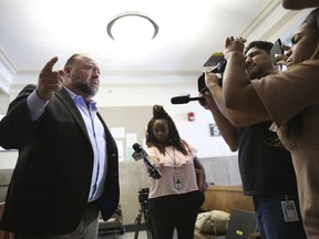 Alex Jones talks to media during a midday break during the trial at the Travis County Courthouse in Austin, Texas, Tuesday, July 26, 2022. An attorney for the parents of one of the children who were killed in the Sandy Hook Elementary School shooting told jurors that Jones repeatedly "lied and attacked the parents of murdered children" when he told his Infowars audience that the 2012 attack was a hoax. Attorney Mark Bankston said during his opening statement to determine damages against Jones that Jones created a "massive campaign of lies" and recruited "wild extremists from the fringes of the internet ... who were as cruel as Mr. Jones wanted them to be" to the victims' families. Jones later blasted the case, calling it a "show trial" and an assault on the First Amendment.