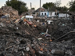 People stand next to a residential house destroyed by a Russian military strike, as Russia's attack on Ukraine continues, in Chaplyne, Dnipropetrovsk region, Ukraine Aug. 24, 2022.