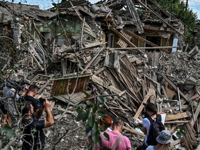 People stand next to a residential house destroyed by a Russian missile strike in the settlement of Kushuhum, as Russia’s attack on Ukraine continues, in Zaporizhzhia region, Ukraine Aug. 10.