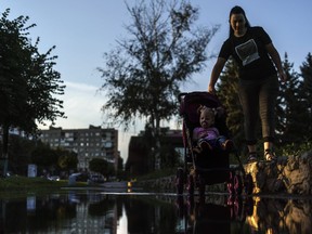 A mother pushes her child in a carriage through a puddle after a rainstorm in Pokrovsk, Donetsk region, eastern Ukraine, Thursday, Aug. 4, 2022.