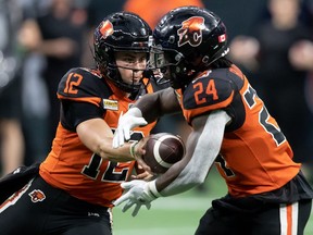 B.C. Lions quarterback Nathan Rourke (12) hands off to James Butler (24) during the first half of CFL football game against the Hamilton Tiger-Cats in Vancouver, on Thursday, July 21, 2022.