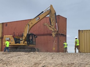 FILE - This photo provided by the Arizona Governor's Office shows shipping containers that will be used to fill a 1,000 foot gap in the border wall with Mexico near Yuma, Ariz., on Aug. 12, 2022. Two will be stacked atop each other and then topped with razor wire to slow migrants from crossing into Arizona. Authorities say migrants were stopped fewer times at the U.S. border with Mexico in July than in June, a second straight monthly decline. (Arizona Governor's Office via AP)