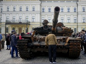 FILE - A man looks at a destroyed Russian tank placed as a symbol of war in downtown Kyiv, Ukraine, May 23, 2022. A new report from NewsGuard, a tech firm that tracks disinformation has identified 250 websites actively working to spread Kremlin disinformation.