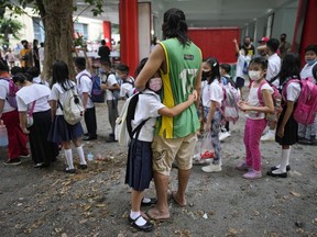 A girl holds on to his father during the opening of classes at the San Juan Elementary School in Pasig, Philippines on Monday, Aug. 22, 2022. Millions of students wearing face masks streamed back to grade and high schools across the Philippines Monday in their first in-person classes after two years of coronavirus lockdowns that are feared to have worsened one of the world's most alarming illiteracy rates among children.