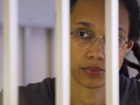 WNBA star and two-time Olympic gold medalist Brittney Griner looks through bars as she listens to the verdict standing in a cage in a courtroom in Khimki just outside Moscow, Russia, Thursday, Aug. 4, 2022. A judge in Russia has convicted American basketball star Brittney Griner of drug possession and smuggling and sentenced her to nine years in prison.