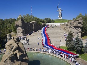 People carry a giant Russian flag during celebration of the Day of The National Flag in Mamayev Kurgan, the World War II Battle of Stalingrad memorial, in Volgograd, Russia, Monday, Aug. 22, 2022.