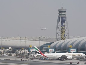 FILE- An Emirates Boeing 777 stands at the gate at Dubai International Airport as another prepares to land on the runway in Dubai, United Arab Emirates, Wednesday, Aug. 17, 2022. Emirates will suspend all flights to Nigeria from September 1 over its failure to repatriate millions of its funds it said are blocked in the West African nation, the Dubai-based airline announced on Thursday, Aug. 17, 2022. The airline -- which has been battling to repatriate its millions of dollars in revenue from Nigeria -- said in a statement that it took the "difficult decision" to limit further losses, citing circumstances "beyond our control."