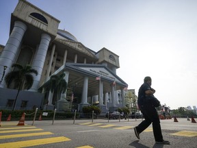 A person passes in front of the High Court as former Prime Minister Najib Razak is planning to attend a hearing related to another case filed against him involving the 1MDB scandal in Kuala Lumpur, Malaysia, Thursday, Aug. 25, 2022. Najib started his 12-year prison sentence Tuesday after losing his final appeal in a graft case linked to the looting of the 1MDB state fund, with the top court unanimously upholding his conviction and sentence.