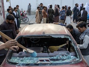 Afghan people clean a car that was damaged by an explosion, in Kabul, Afghanistan, Wednesday, Sept. 21, 2022. Major humanitarian groups are urging the Trudeau government to loosen its restrictions on working with the Taliban in Afghanistan.