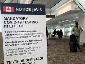 Travelers walk past a "Mandatory COVID-19 Testing" sign at Pearson International Airport in Toronto, in 2021.