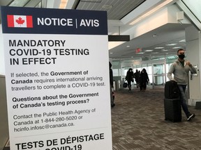 Travelers walk past a "Mandatory COVID-19 Testing" sign at Pearson International Airport in Toronto, in 2021.