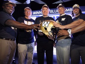 FILE -- The new Winnipeg Blue Bombers 1980s-style logo is shown off by Bombers alumni and players (left to right) James Murphy, Bob Cameron, Joe Poplawski, Ken Ploen, and Chris Cvetkovic at a press conference at Canada Inn Stadium in Winnipeg, Tuesday, April 24, 2012. The Blue Bombers will add former receiver Poplawski to the club's Ring of Honour at IG Field.&ampnbsp;THE CANADIAN PRESS/John Woods