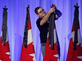 A person ties black ribbons to Canadian flags as symbols of mourning for Britain's Queen Elizabeth before Canada's Conservative Party leadership election in Ottawa, Ontario, Canada, September 10, 2022.