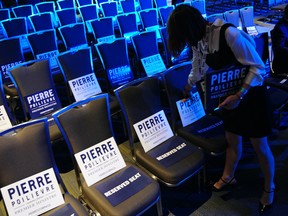 A supporter places signs for candidate Pierre Poilievre on seats at the Conservative Party of Canada leadership vote, in Ottawa, Saturday, Sept. 10, 2022. THE CANADIAN PRESS/Sean Kilpatrick
