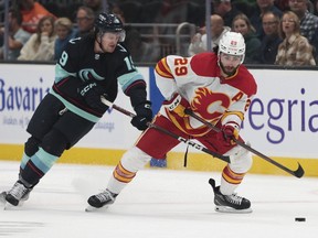 Calgary Flames center Dillon Dube (29) moves the puck as Seattle Kraken center Jared McCann defends during the first period of a preseason NHL hockey game Tuesday, Sept. 27, 2022, in Seattle.