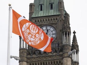 The Survivor's flag flies on Parliament Hill beside the Peace Tower, in Ottawa, Monday, Aug. 29, 2022. The Survivors' Flag was raised at the B.C. legislature Wednesday in a ceremony that Indigenous Relations and Reconciliation Minister Murray Rankin called "profound and moving."