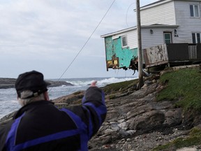 Eine Person zeigt nach der Ankunft des Hurrikans Fiona in Port Aux Basques, Neufundland, Kanada, am 25. September 2022 auf ein beschädigtes Haus.