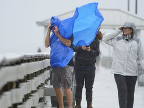 People walk on the Ballast Point Pier ahead of Hurricane Ian, Wednesday, Sept. 28, 2022, in Tampa, Fla. The U.S. National Hurricane Center says Ian's most damaging winds have begun hitting Florida's southwest coast as the storm approaches landfall.