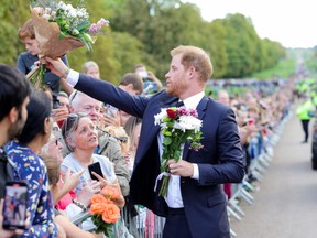 Prince Harry, Duke of Sussex receives flowers from the crowds of public on the long Walk at Windsor Castle on September 10, 2022 in Windsor, England.
