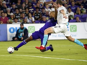 Orlando City's Tesho Akindele, left, attempts a shot on goal as New England Revolution's Henry Kessler defends during the second half of an MLS soccer match Saturday, Aug. 6, 2022, in Orlando, Fla.