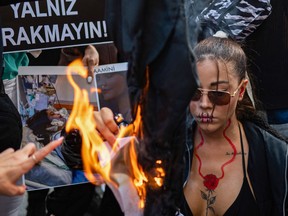 Protesters set fire to material as they hold a banner with the portrait of Iranian Mahsa Amini, while they take part in a rally outside the Iranian consulate in Istanbul on Sept. 29.
