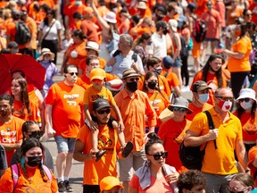 Rally participants hold up signs and wear orange shirts as they march down Portage Ave in support of residential school survivors and the families of missing and murdered Indigenous children in Winnipeg, Thursday, 
July 1, 2021. THE CANADIAN PRESS/Mike Sudoma