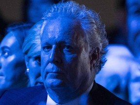 Bathed in Conservative-blue light, Jean Charest listens to Pierre Poilievre's leadership victory speech on September 10, 2022.