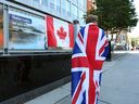 Die Trauernde Eissa Saddozai, die in eine Union Jack-Flagge gehüllt ist, steht nach dem Tod von Königin Elizabeth II. am 8. September 2022 vor der britischen Hochkommission in Ottawa.