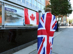Mourner Eissa Saddozai draped in a Union Jack flag stands in front of the British High Commission in Ottawa after the death of Queen Elizabeth II on September 8, 2022,