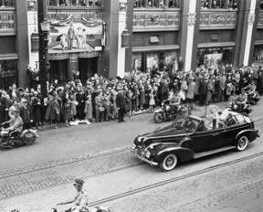 King George VI and Queen Elizabeth look up at the photo of themselves on the side of the Toronto Star building.