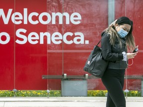 A pedestrian wearing a mask walks at Seneca College campus in Toronto, May 5, 2021. Currently, the college requires all students who access the campus to be fully vaccinated for COVID-19.