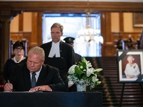Michelle DiEmanuele, Secretary of the Cabinet and Head of the Ontario Public Service, and Ted Arnott, Speaker of the Legislative Assembly of Ontario, look on as Premier Doug Ford, centre, signs Ontario's book of condolence in honour of the passing of Queen Elizabeth II at Queen's Park in Toronto, Friday, Sept. 9, 2022. Members of Ontario's legislature are set to pay tribute today to Queen Elizabeth II.