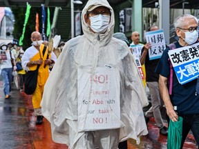 A man with an anti-Abe placard takes part in a march with other protesters against the government's funding for the funeral of late Japanese prime minister Shinzo Abe, along a street in Tokyo on Sept. 19.