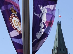 The flag on the Peace Tower flies at half-mast behind banners of Queen Elizabeth celebrating the Platinum Jubilee, in Ottawa, Thursday, Sept.8, 2022. Members of Parliament of all political stripes are expected to rise in tribute to the late Queen Elizabeth today during a special sitting of the House of Commons.