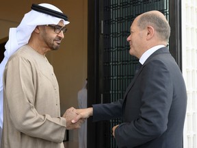 In this photo made available by the United Arab Emirates Presidential Court, Sheikh Mohamed bin Zayed Al Nahyan, President of the UAE left, shakes hands with German Chancellor Olaf Scholz, at Al Shati Palace in Abu Dhabi, United Arab Emirates, Sunday, Sept. 25, 2022.