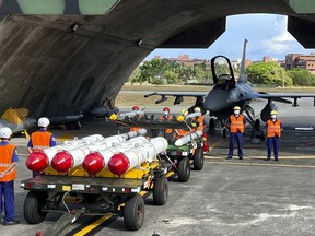Military personnel stand next to U.S. Harpoon A-84, anti-ship missiles and AIM-120 and AIM-9 air-to-air missiles prepared for a weapon loading drills in front of a U.S. F-16V fighter jet at the Hualien Airbase in Taiwan's southeastern Hualien county, Wednesday, Aug. 17, 2022. China announced sanctions on Friday, Sept. 16, 2022, against the CEOs of American defense contractors Raytheon and Boeing Defense over a major U.S. arms sale to rival Taiwan.
