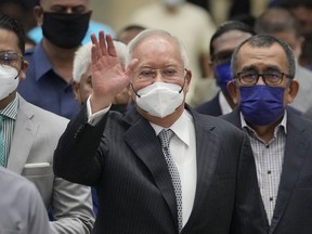 FILE - Former Malaysian Prime Minister Najib Razak, center, wearing a face mask, waves as he arrives at the Court of Appeal in Putrajaya, Malaysia, Tuesday, Aug. 23, 2022. Jailed Malaysian ex-Prime Minister Najib Razak returned to court Thursday for a second corruption trial over the pilfering of the 1MDB state fund, two days after he began a 12-year prison term for graft.